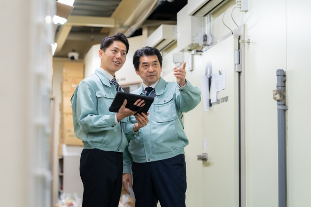業務用冷蔵庫の前で打ち合わせ中の作業員